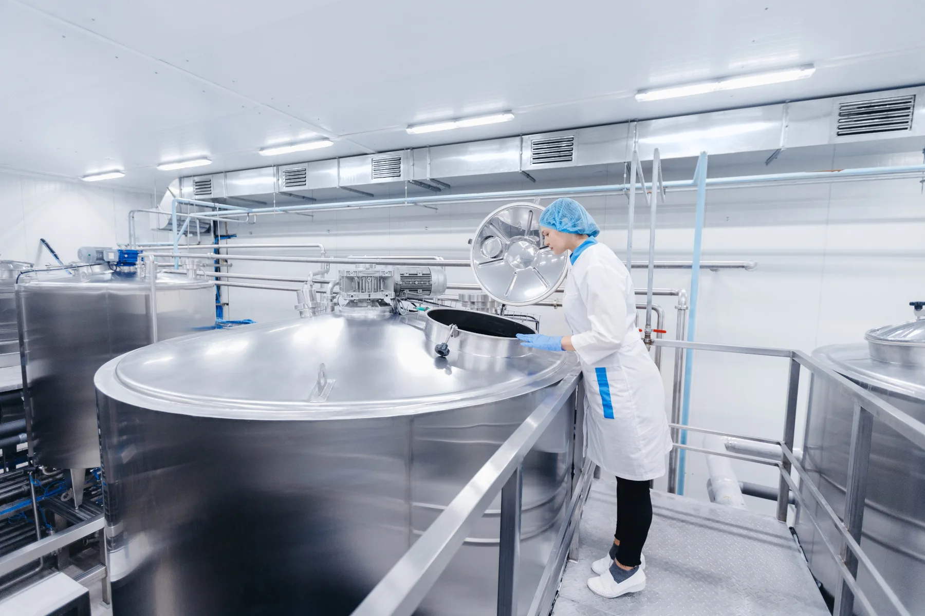 Dairy production, operator woman engineer checks temperature of steel tank with milk. Industrial worker concept AI kaasfabriek